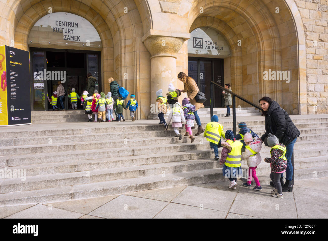 Los jóvenes escolares de niños y niñas vestían chaquetas de alta visibilidad y la ropa que se llevó en un cocodrilo por maestros en el teatro en Poznan, Polonia Foto de stock