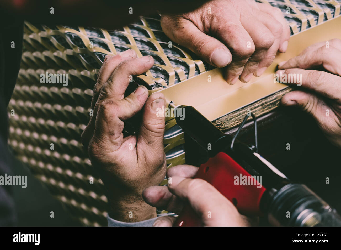 Los trabajadores que ensamblan monturas de metal con una pistola de remaches en la línea de producción. Foto de stock