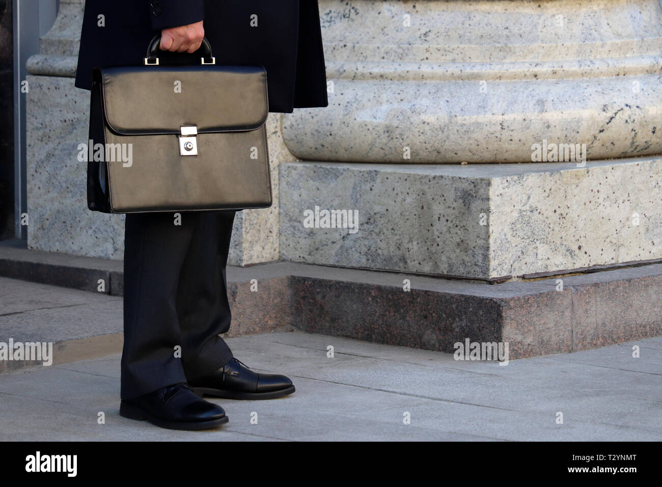 Sumergido pereza Repetirse Hombre en un traje de negocios con un maletín de cuero exterior permanente.  Concepto de empresario, funcionario, político, carrera Fotografía de stock  - Alamy