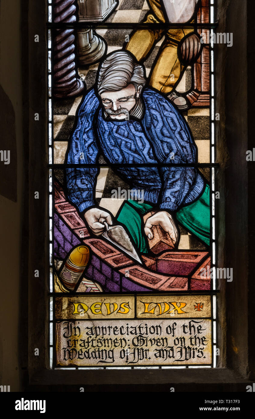 Las vidrieras modernas, mostrando un albañil en el trabajo, la iglesia de San Nicolás, Potterspury, Northamptonshire, Reino Unido Foto de stock
