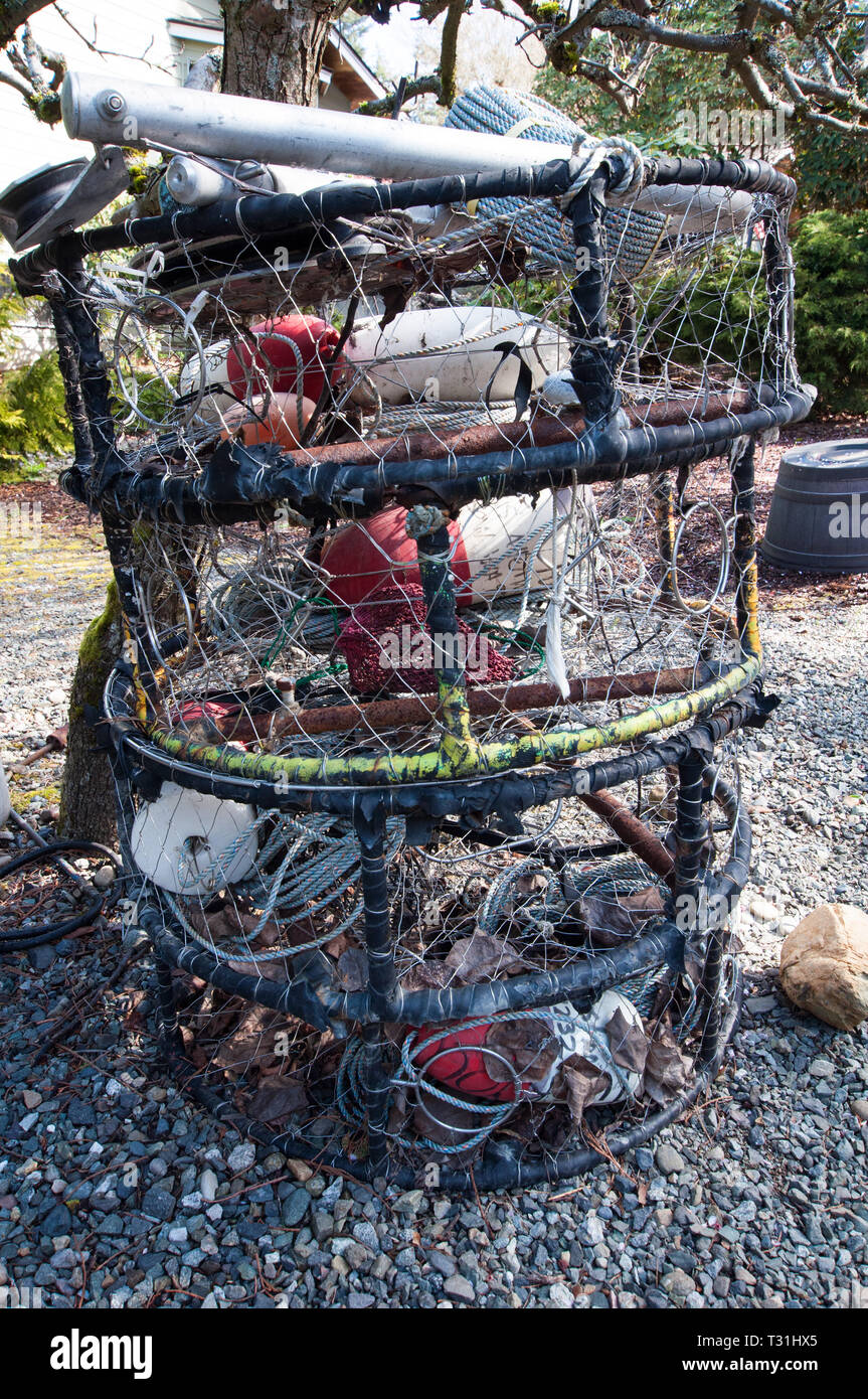 Esta imagen vertical tiene cosas y equipo de pesca en un patio mientras  esperan ser puestos en un barco. Redes, cuerdas, ollas, almejas o cangrejo,  boyas y redes Fotografía de stock 