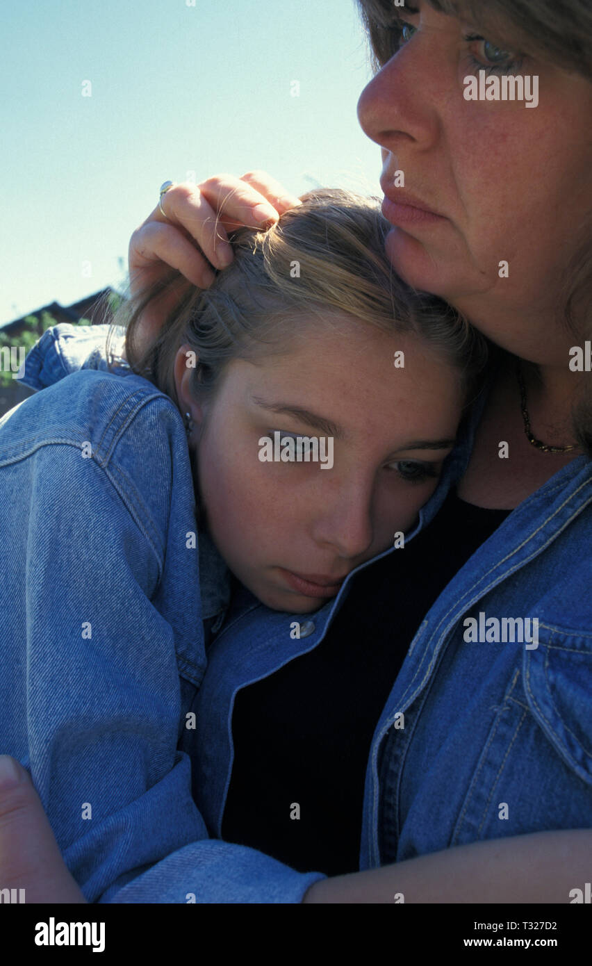 Mujer acunando ansioso adolescente contra su pecho Foto de stock