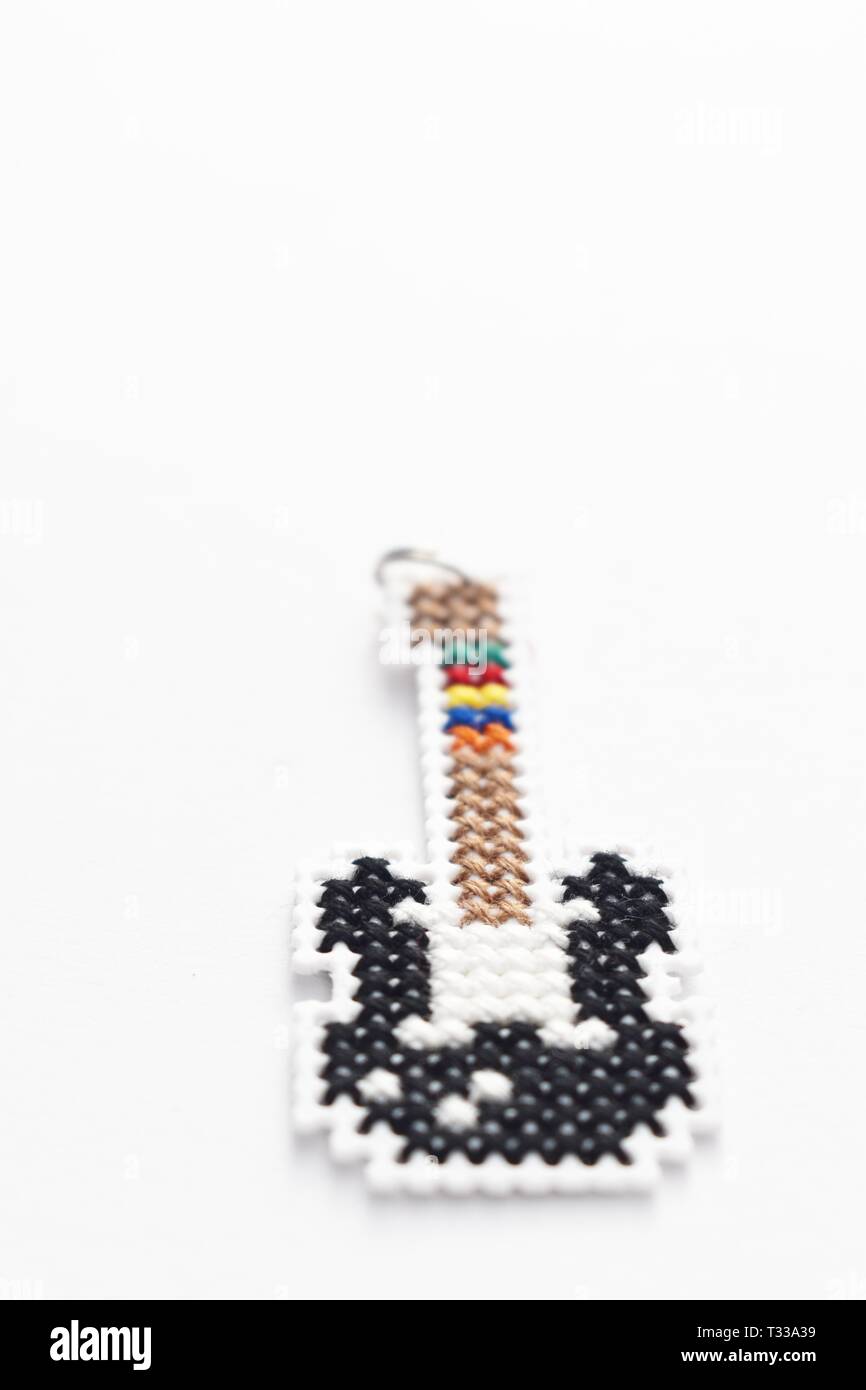Punto de cruz Handmade necklace guitarra bordado sobre lienzo de plástico blanco. Foto de stock