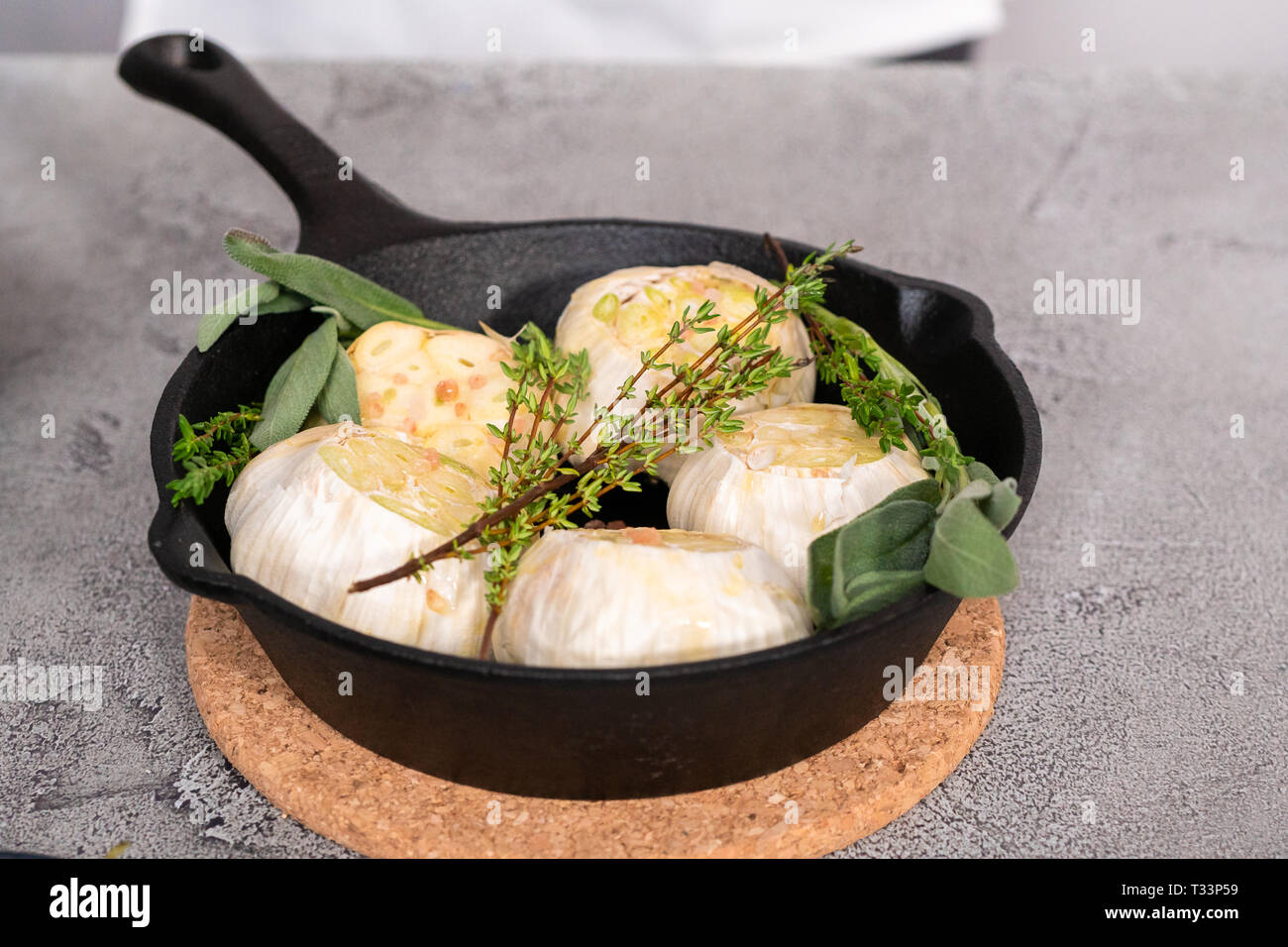 Cabezas de ajo crudo con especias frescas en sartén de hierro fundido para  preparar recetas de ajo asado Fotografía de stock - Alamy