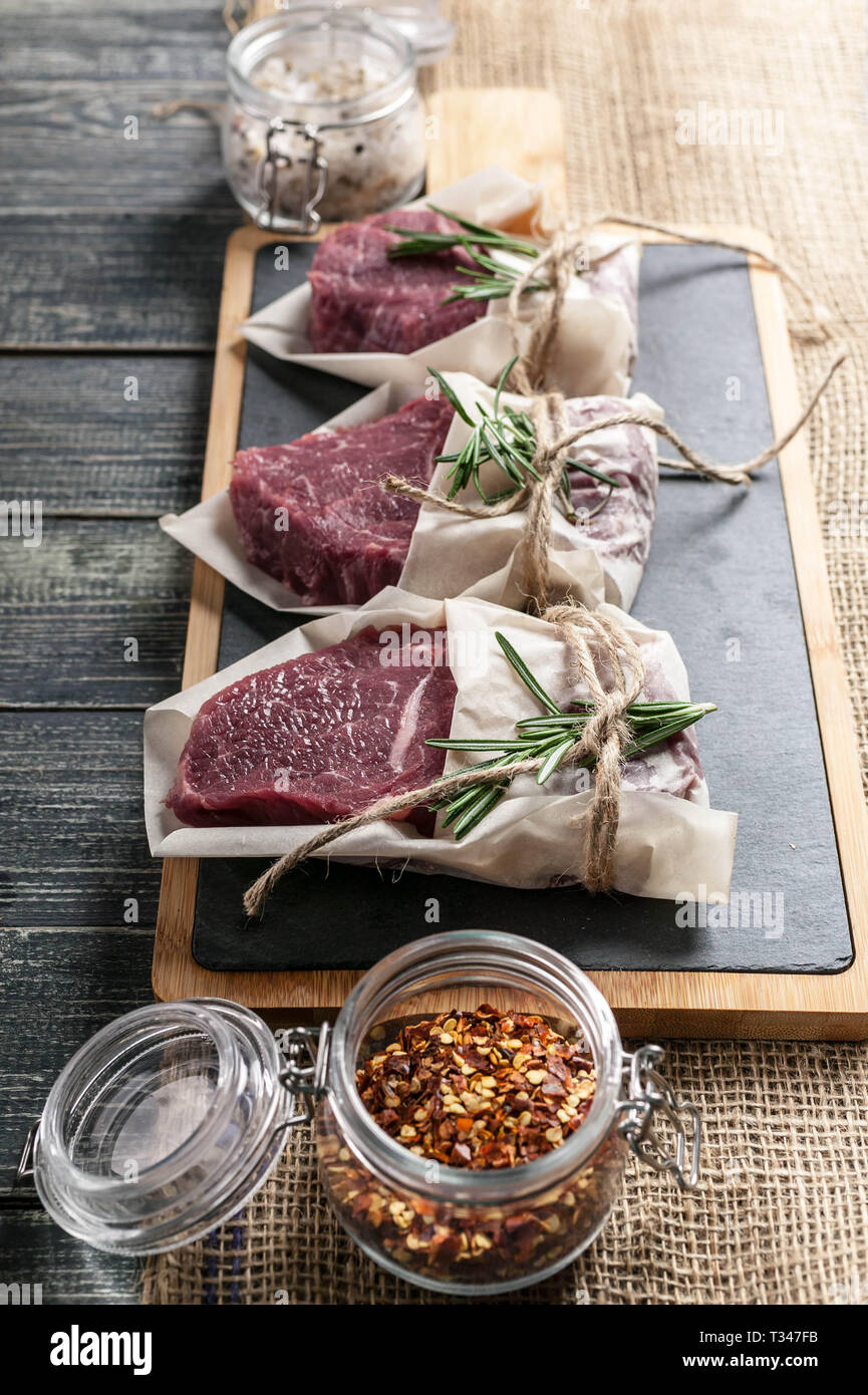 Filetes de carne cruda y verduras. Carne fresca en una tabla para cortar Foto de stock