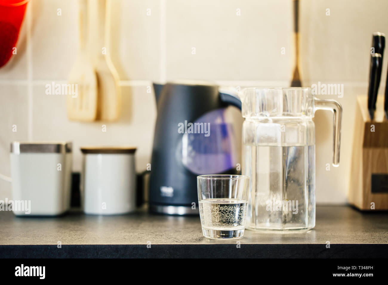 Vaso de agua pura y la jarra en la mesa de la cocina. Foto de stock