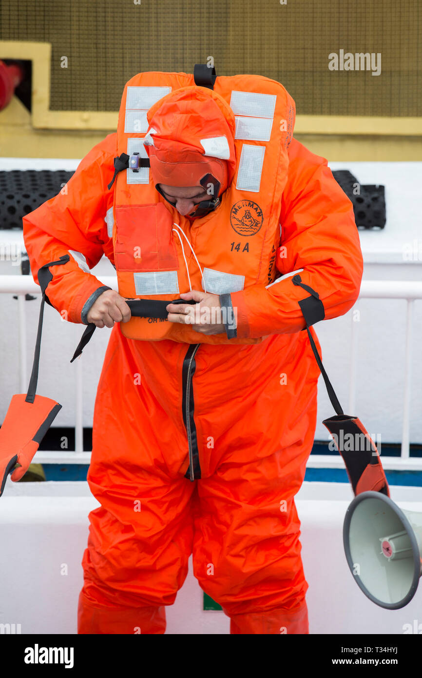 La tripulación y los pasajeros pasan por un taladro de seguridad en un  barco de crucero Antártica con la tripulación que muestra cómo colocar un  traje de supervivencia, diseñado para mantenerle vivo