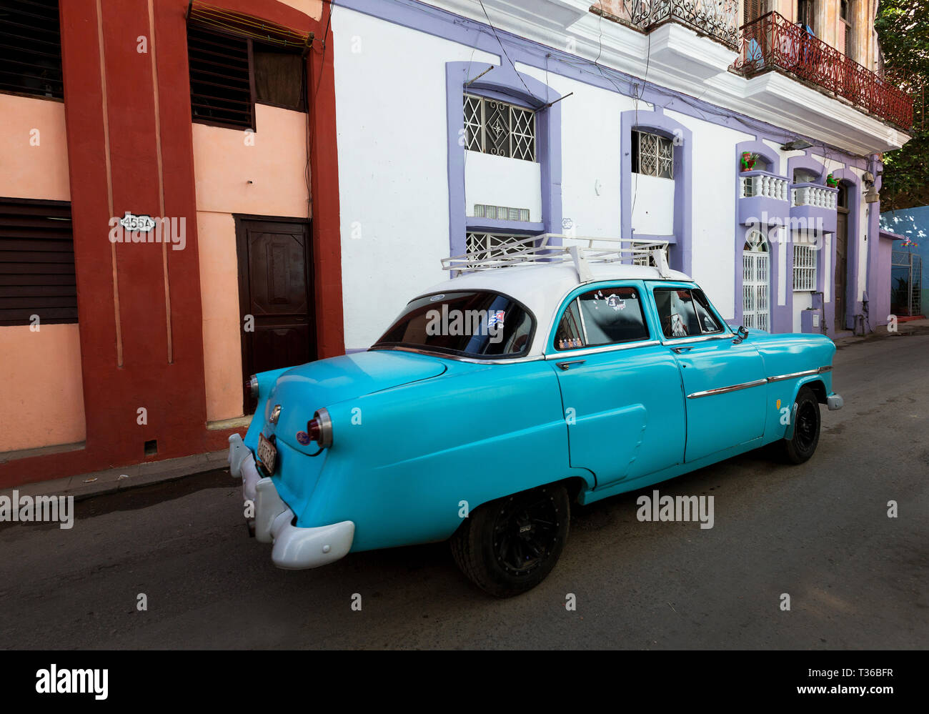 Azul y Blanco 1952 Ford Customline conducción sedán de cuatro puertas de calle con edificios coloridos en La Habana, Cuba Foto de stock