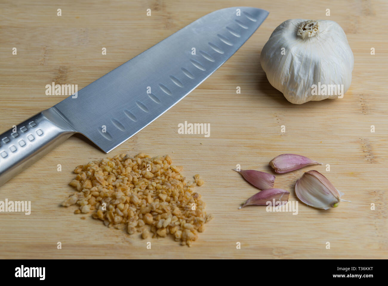 Cuchillo de cocina japonesa ( Santoku ) sobre una tabla para cortar con el ajo, los clavos secos y polvo granulado grueso Foto de stock