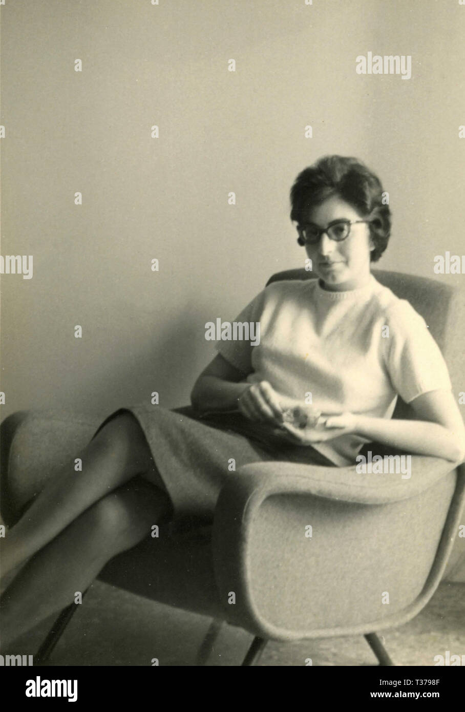 Mujer con gafas sentado en un sillón, Italia 1961 Foto de stock