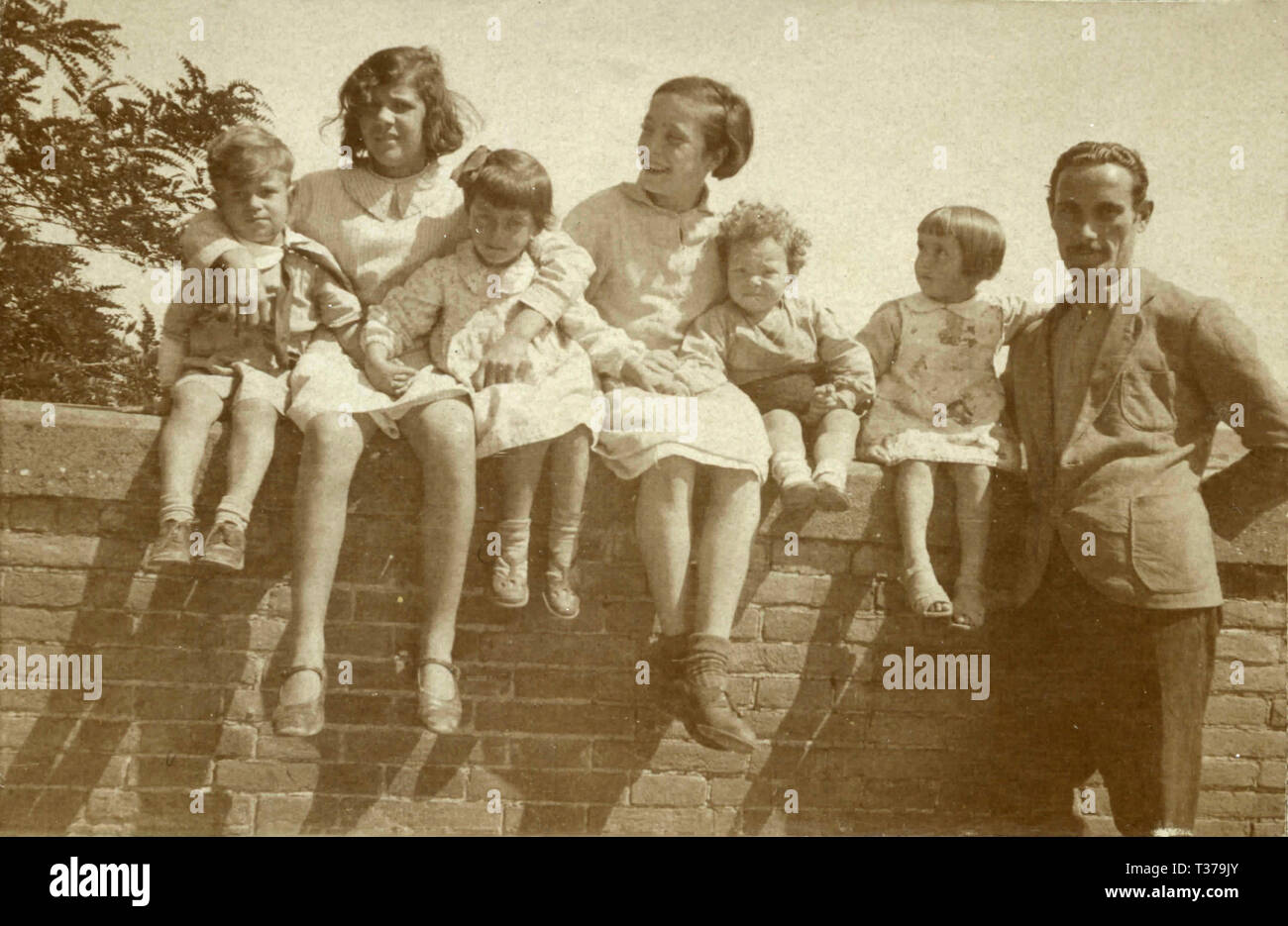 Un grupo de niños sentados en el muro, Italia 1920 Foto de stock