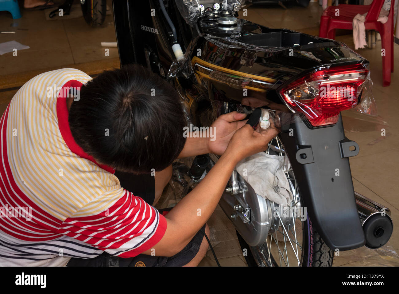 Camboya, Kampong (Kompong Cham), del centro de la ciudad, motocicleta showroom hombre aplicar calcas personalizadas a Honda Dream moto Foto de stock