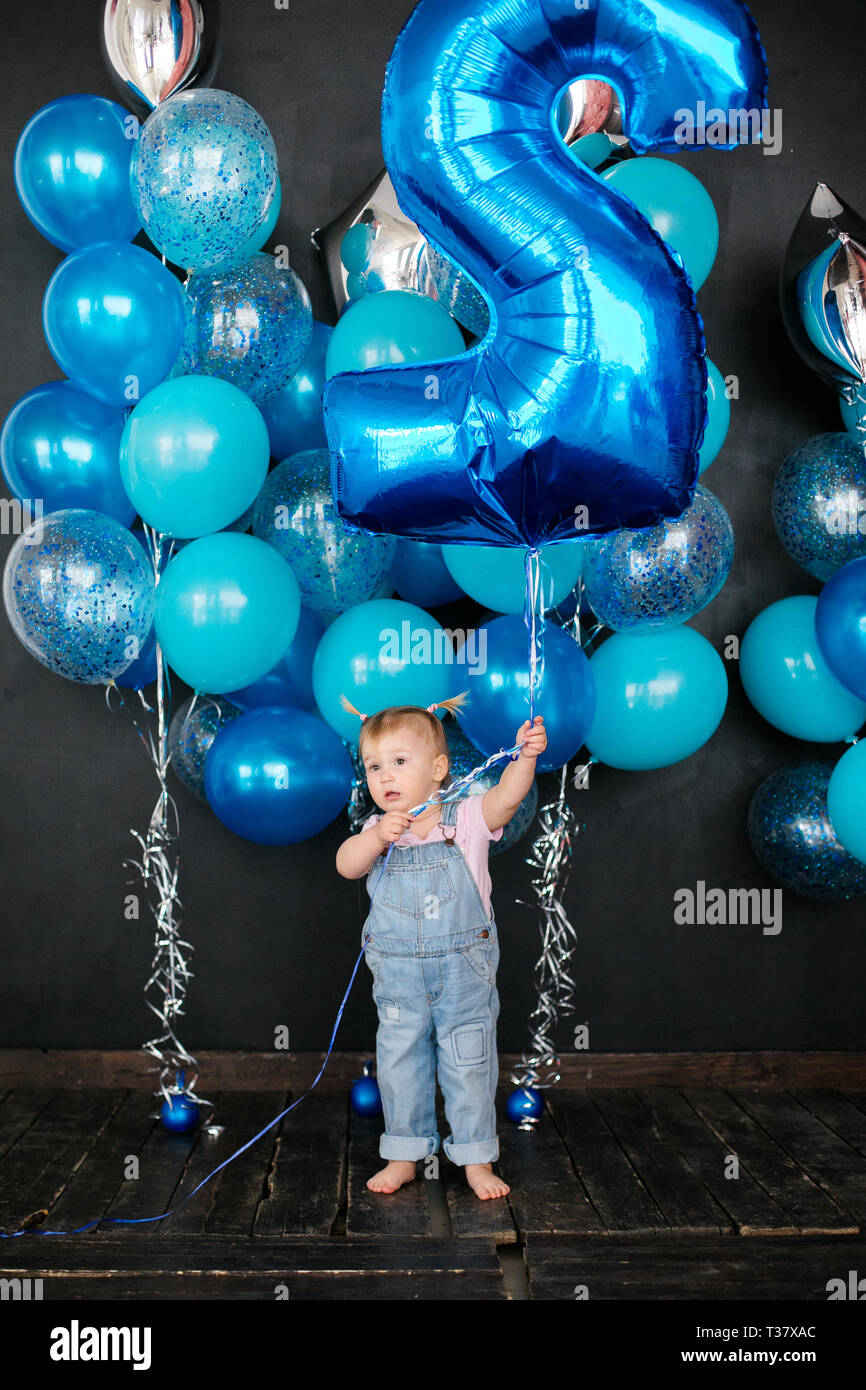 Rubia chica con globos plateados y azules sobre fondo negro. Cumpleaños de  niños de 2 años Fotografía de stock - Alamy