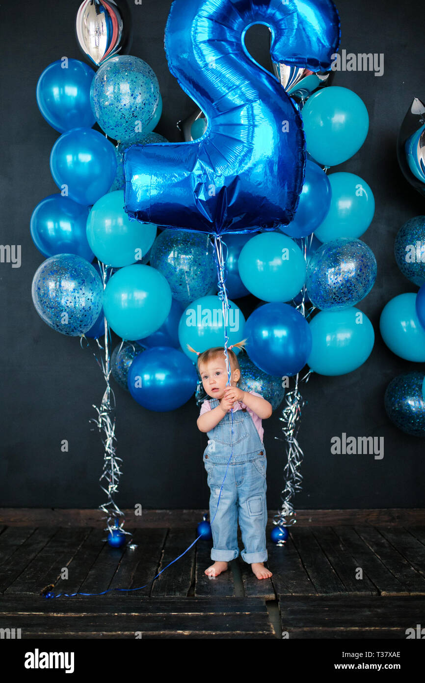 Rubia chica con globos plateados y azules sobre fondo negro. Cumpleaños de  niños de 2 años Fotografía de stock - Alamy