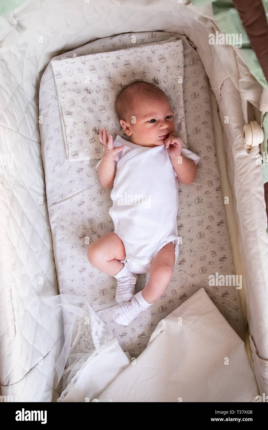 Bebé recién nacido niño en cama. Recién nacido en blanco luz bodykit  acostado en la cuna. Los niños duermen. Ropa de cama para niños. Bebé, una  siesta en la cama. Littl saludable