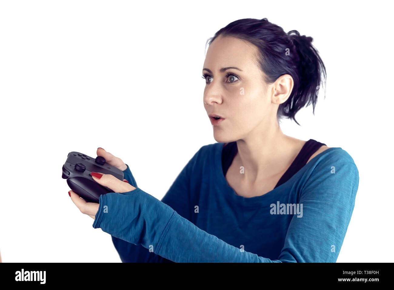 Mujer joven con jersey azul jugar video juegos en el controlador para juegos inalámbrico con un concentrado de expresiones faciales aislado en blanco Foto de stock