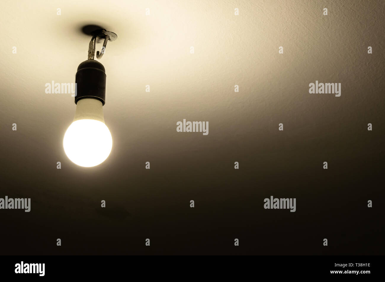 Bombilla de luz sin lámpara colgando del techo en la oscuridad. Iluminación  de un viejo y lúgubre habitación con espacio de copia Fotografía de stock -  Alamy