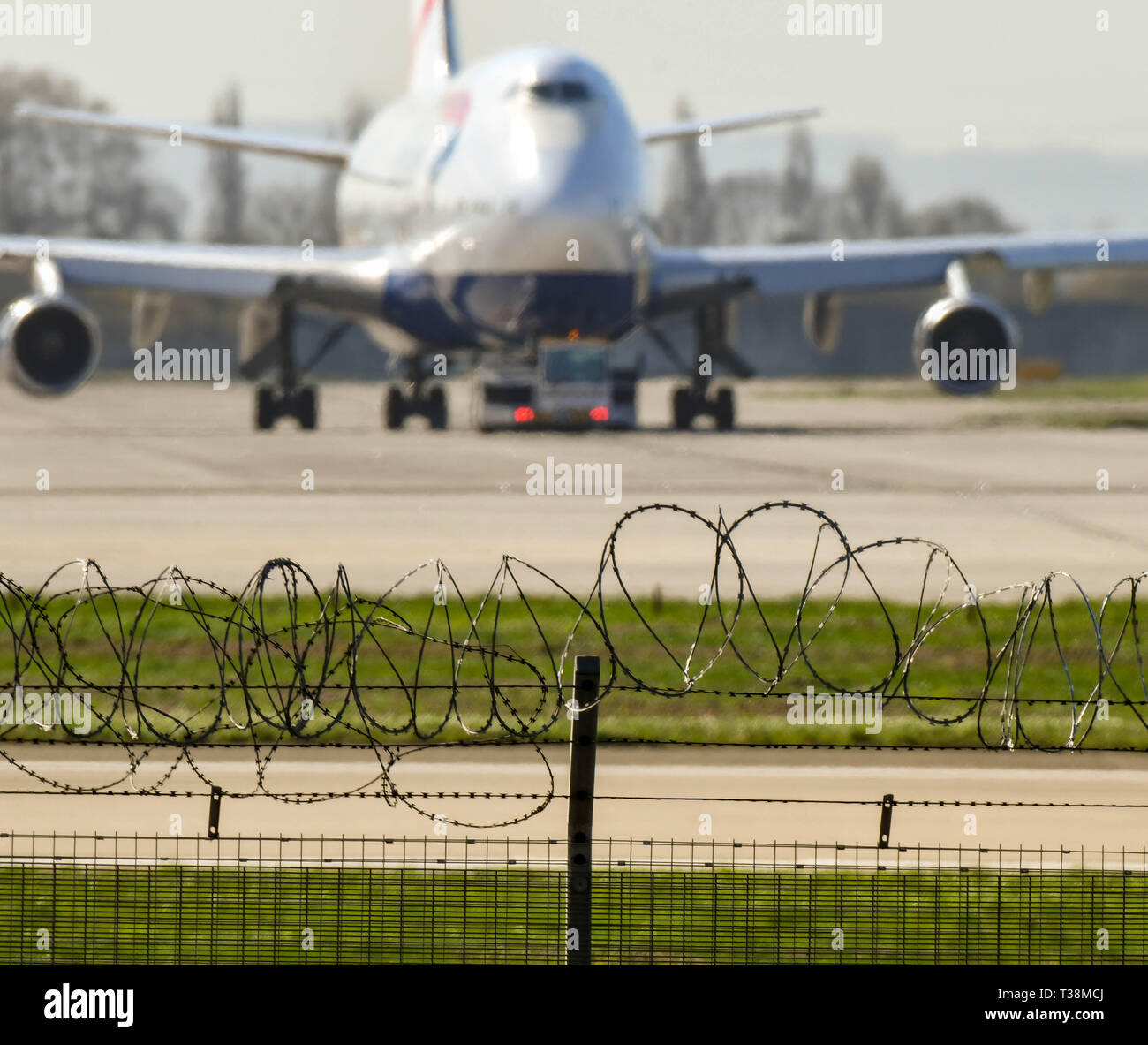 Londres, Inglaterra - Marzo 2019: barrera de seguridad de alambre de espino alrededor del perímetro del aeropuerto de Londres Heathrow. Un avión está en el fondo Foto de stock