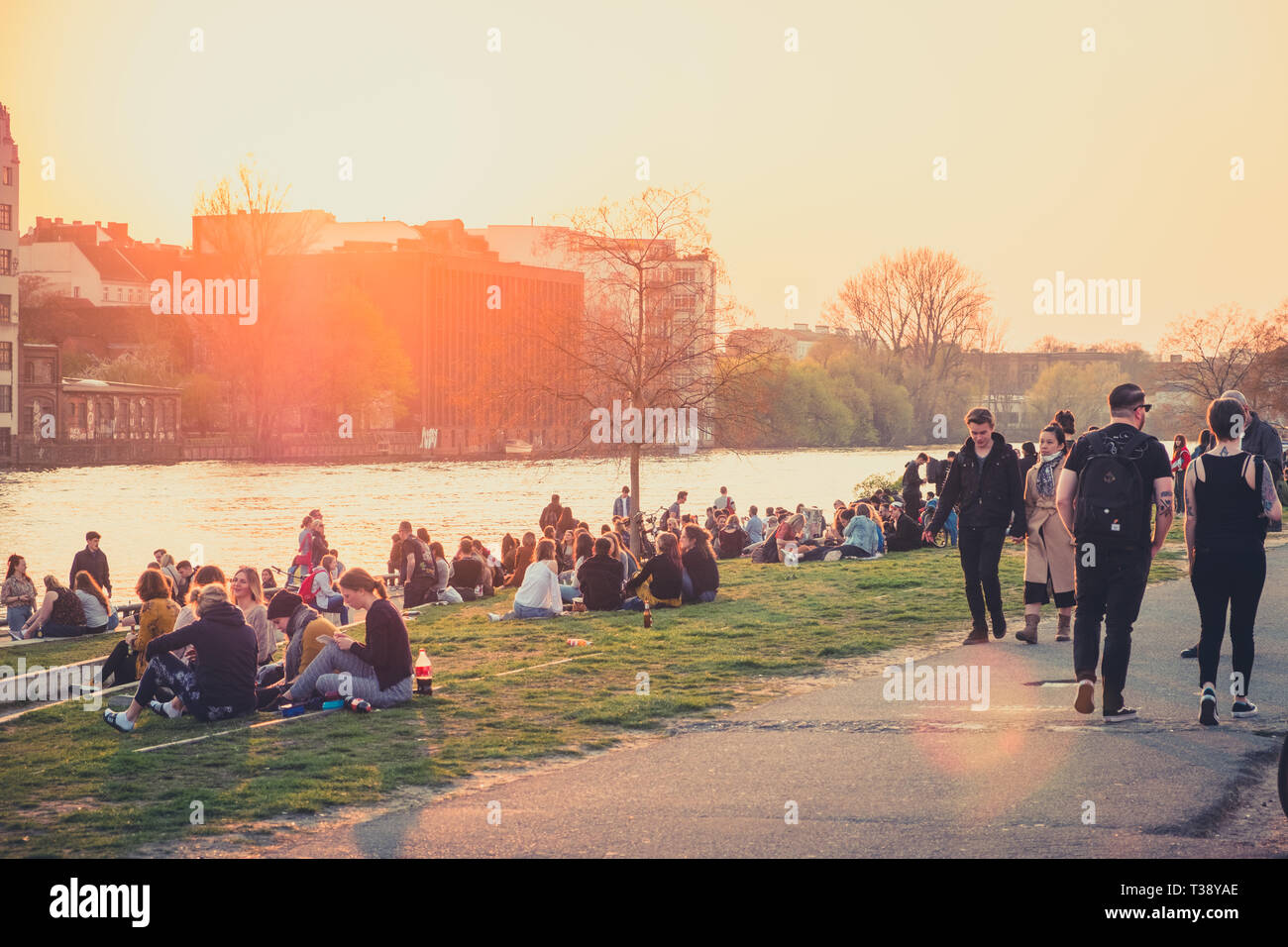 Berlin, Alemania - abril, 2019: la gente en Riverside en el muro de Berlín / East Side Gallery durante la puesta de sol en Berlín, Alemania Foto de stock