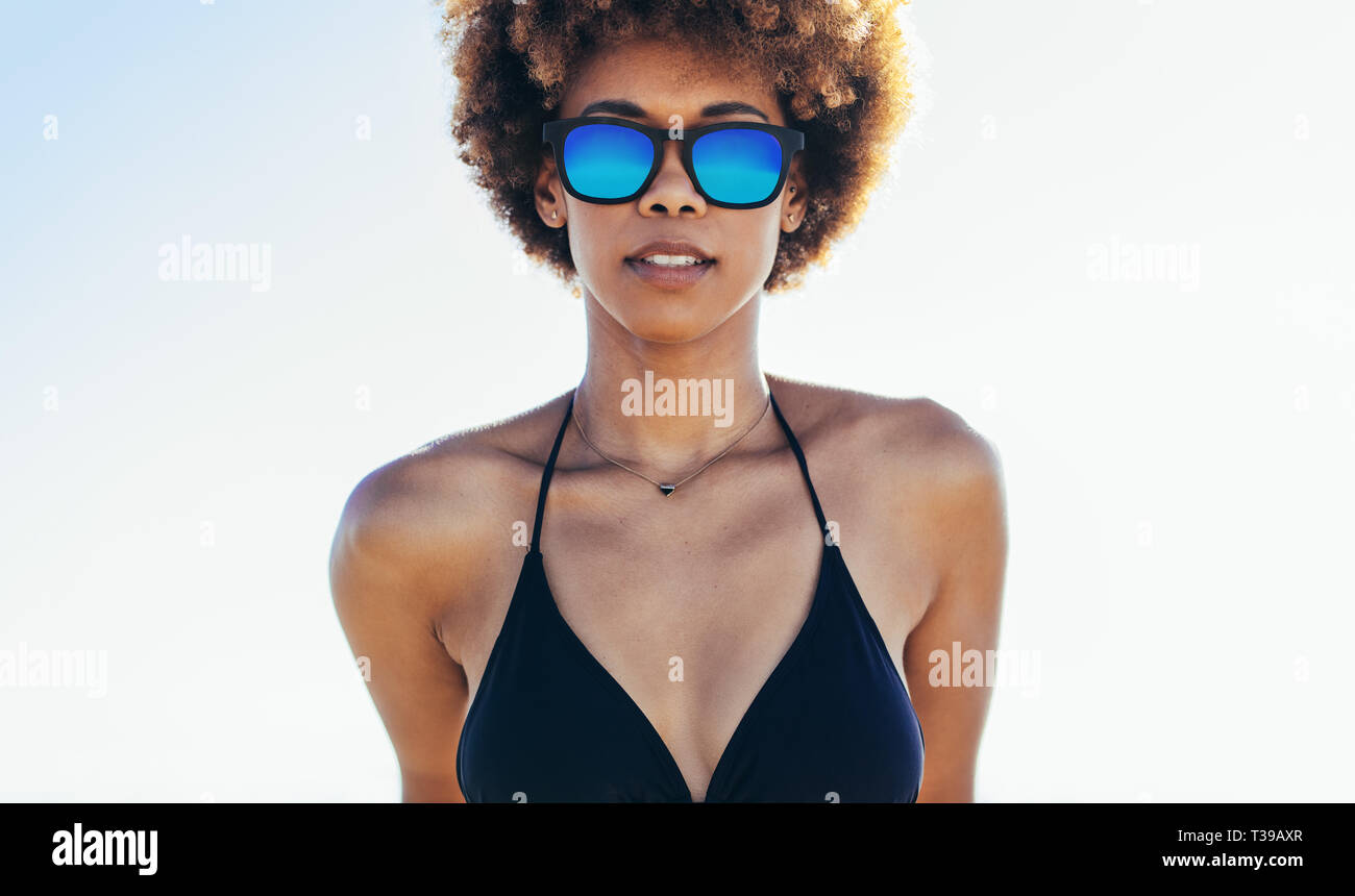 Retrato de hermosa mujer joven en bikini y gafas de sol mirando a la  cámara. Mujeres africanas en bikini negro contra el cielo brillante en  exteriores Fotografía de stock - Alamy