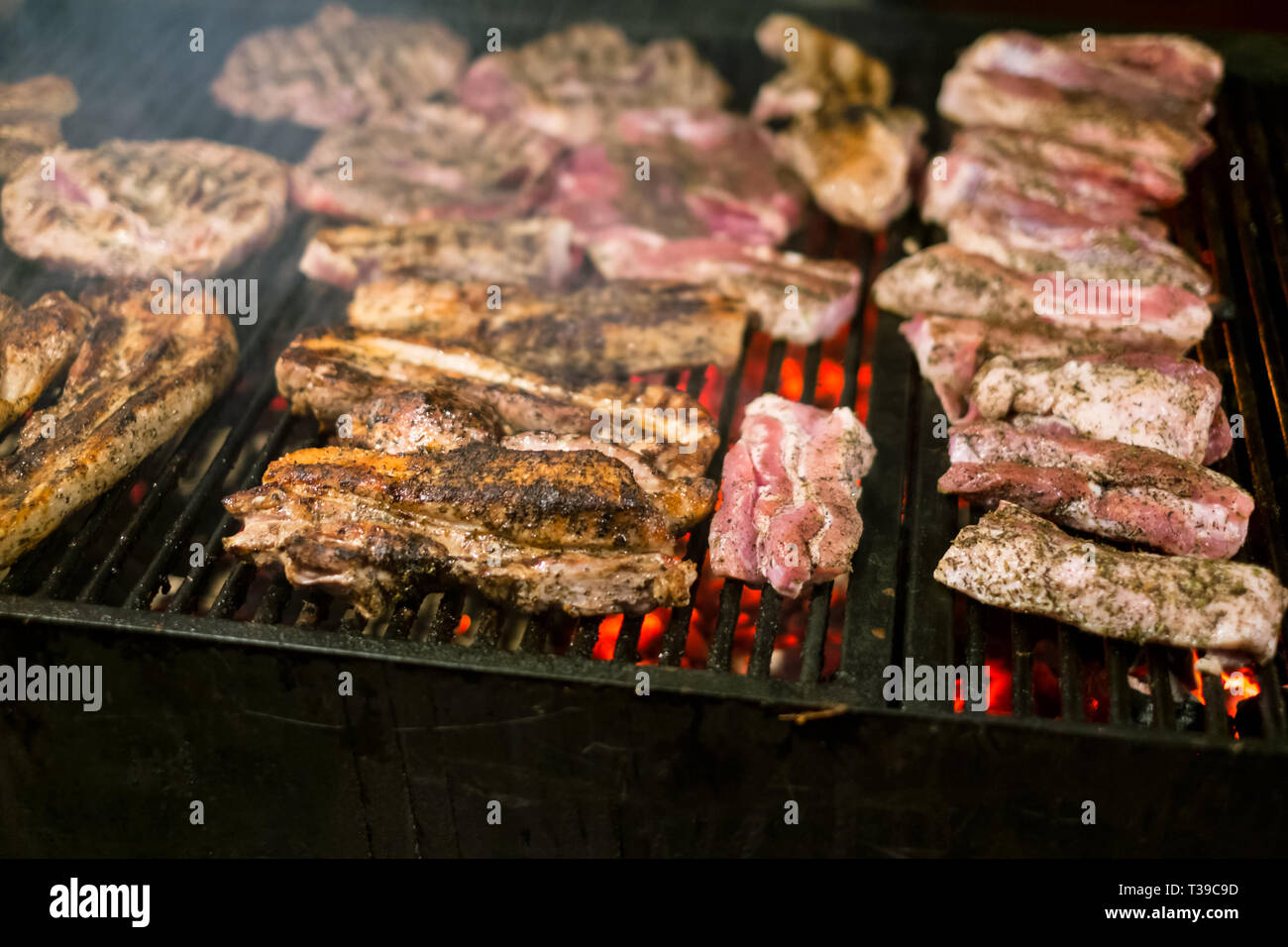 Jugosas carnes asadas cocinadas sobre las brasas de una barbacoa en la  noche Fotografía de stock - Alamy