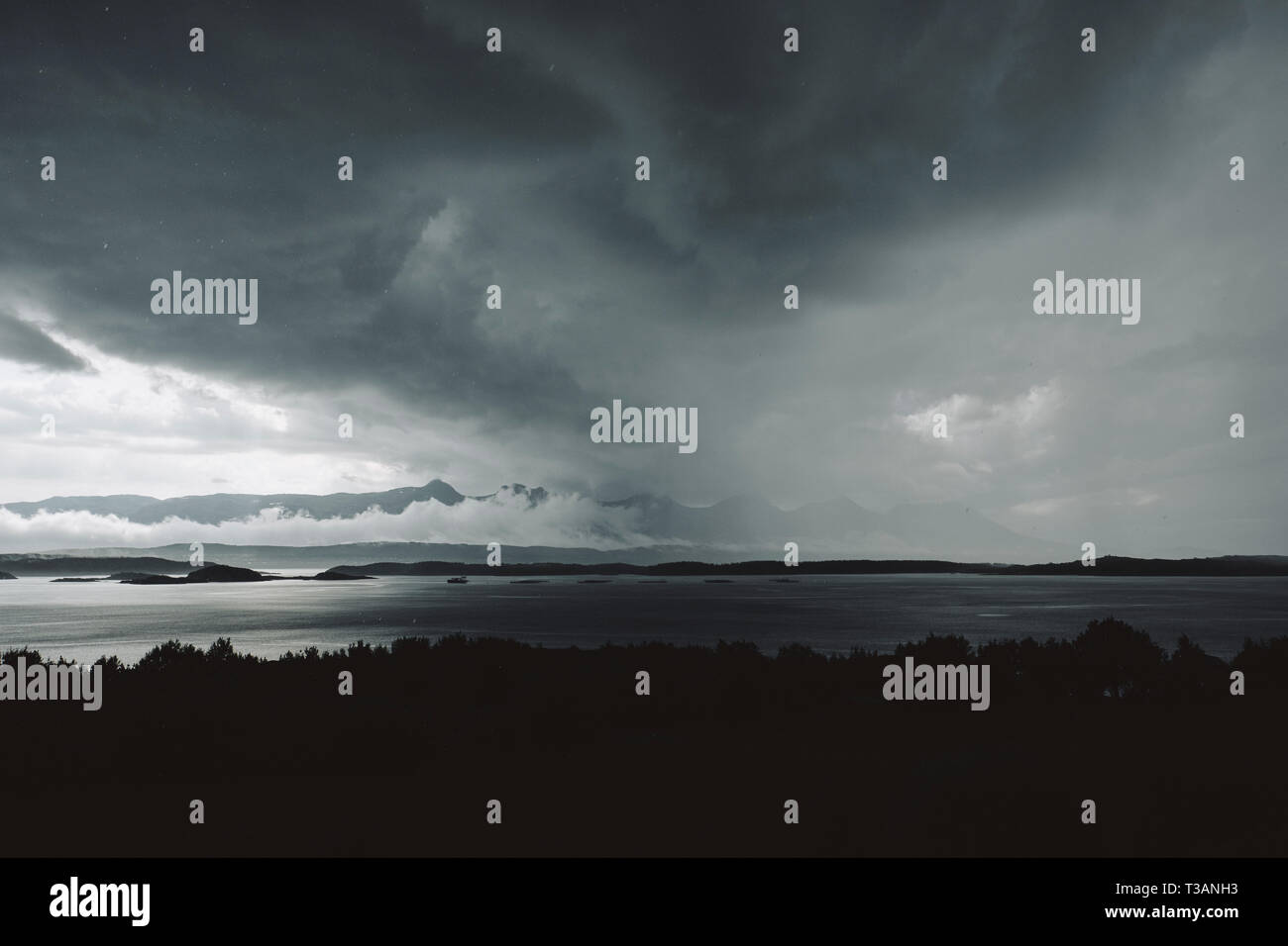 Nubes de tormenta se reúnen en isla Dønna mirando a las Siete Hermanas / De syv søstre cordillera en Helgeland Nordland Noruega Foto de stock