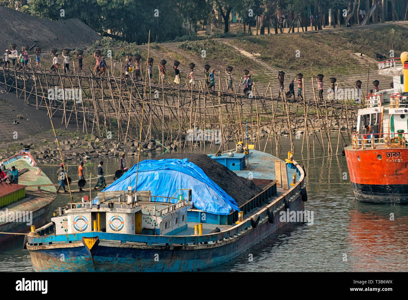 Cargadores cargando carbón en la cabeza, el puerto fluvial de Dhaka, Bangladesh Foto de stock