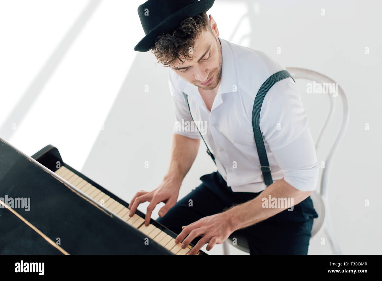 Músico guapo con la camisa blanca y un sombrero negro tocando el piano  Fotografía de stock - Alamy