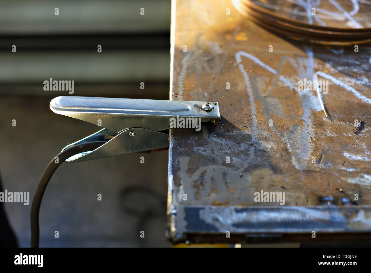 La pinza de puesta a tierra con el cable de la máquina de soldar está  fijado a la tabla de metal sobre la producción. Antecedentes industriales  Fotografía de stock - Alamy