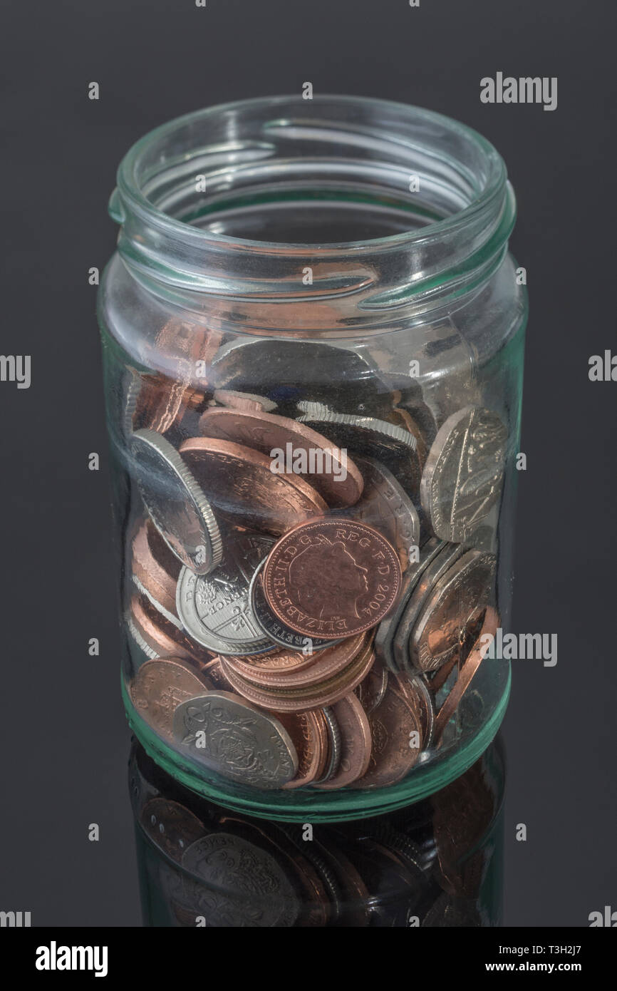 Frasco de vidrio que contiene monedas británicas -como metáfora de los ahorros personales, día lluvioso de ahorro, planes de pensiones, ahorro de bote bote. Foto de stock