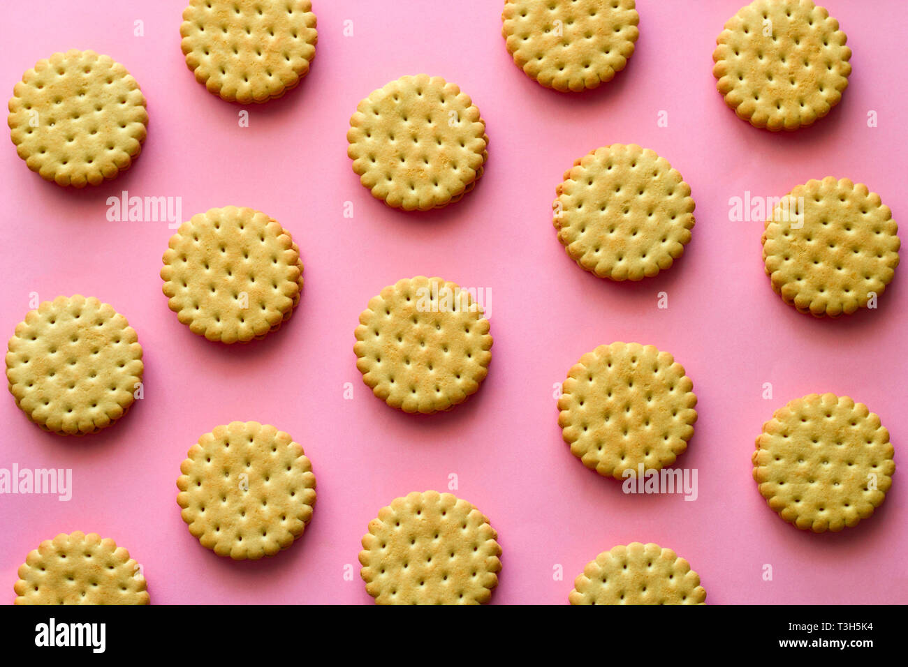 Vista superior todavía creativa vida laical plana cookie filas patrón sobre fondo de color rosa vibrante Foto de stock