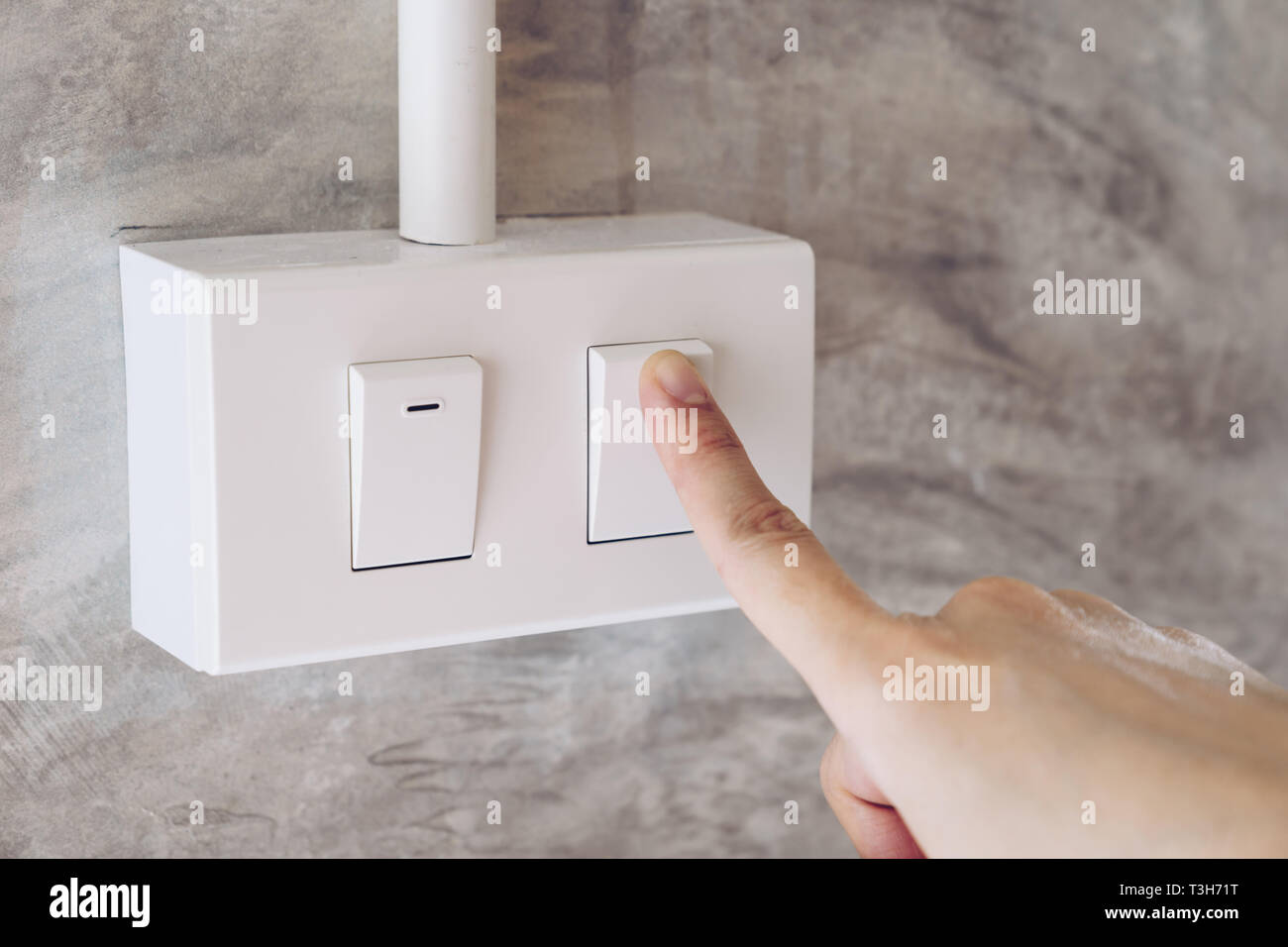 Las mujeres mano encender luces interruptor eléctrico en el muro de cemento antecedentes Foto de stock