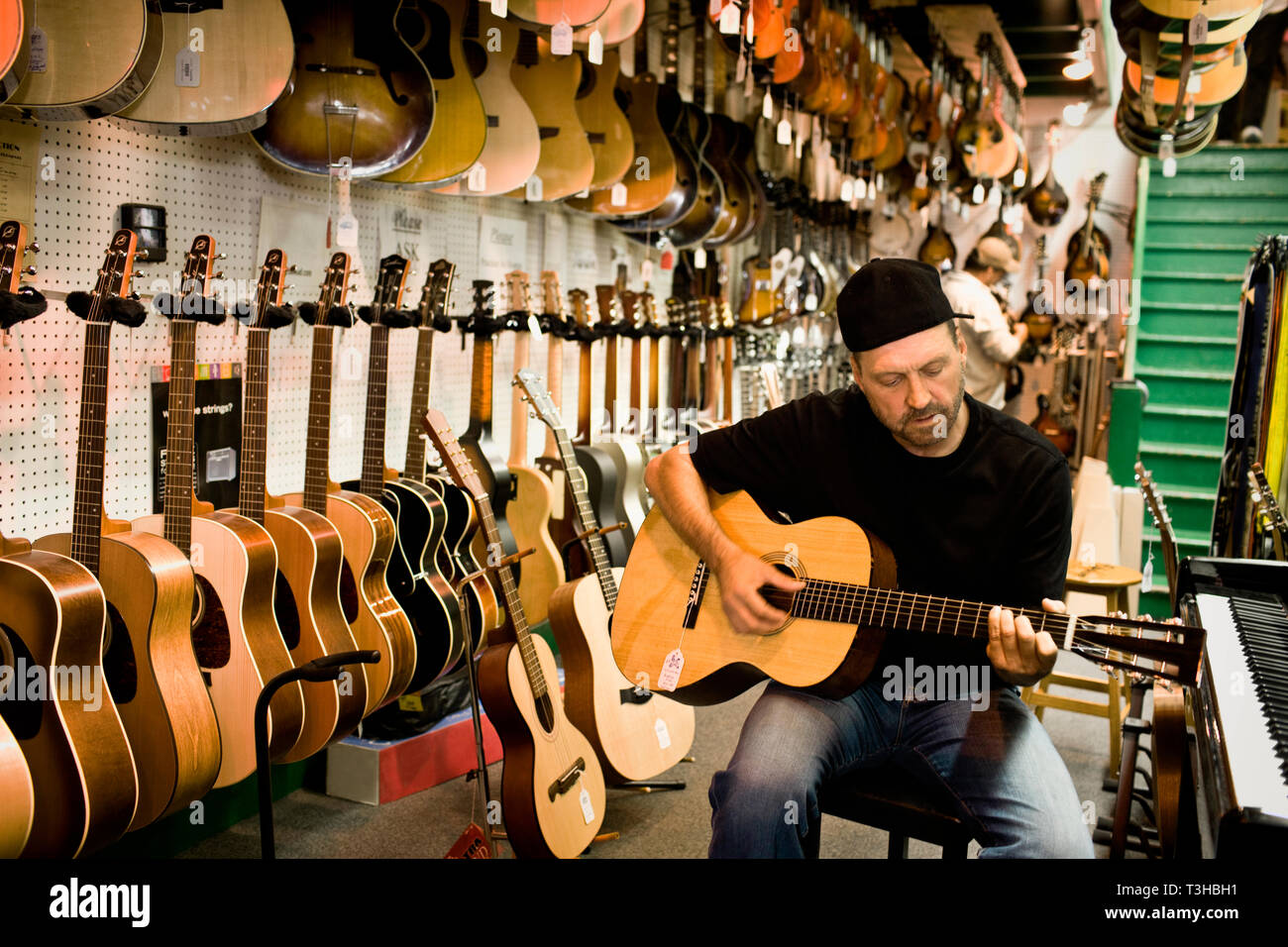El hombre rasga una guitarra acústica en una tienda de música Fotografía de  stock - Alamy