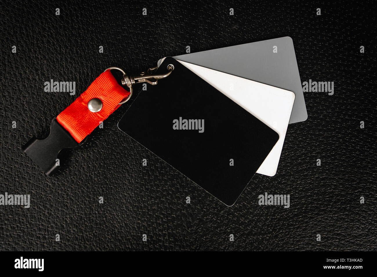 Un conjunto de tarjetas de fotografía del balance de blancos. Un negro, un blanco y un gris, todo en una superficie negra Foto de stock