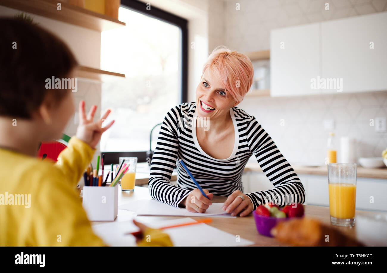 Una mujer joven con la pequeña hija de dibujo en una cocina. Foto de stock