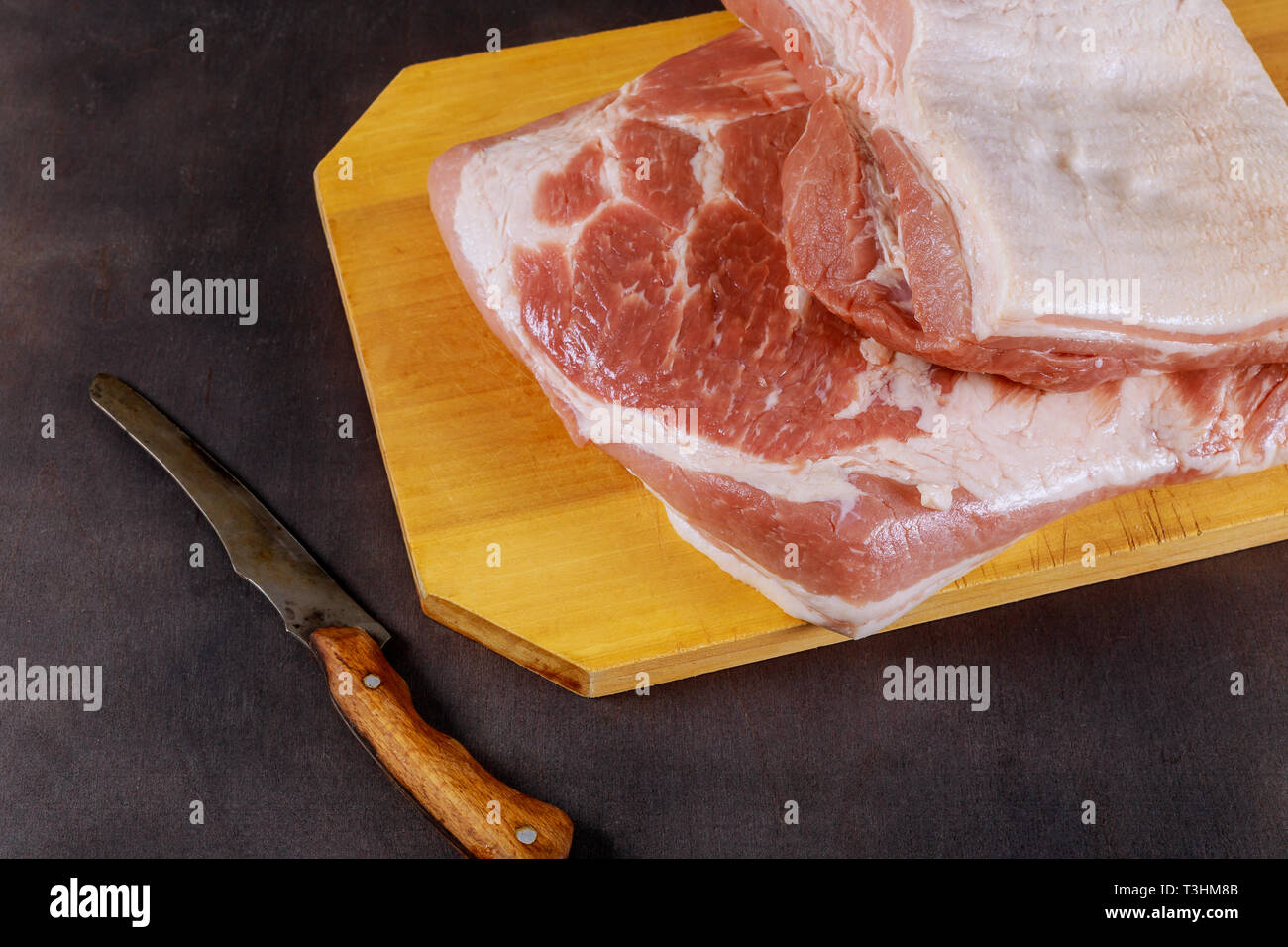 La carne de cerdo cruda de un cerdo con un cuchillo en la tabla de cortar de madera Foto de stock