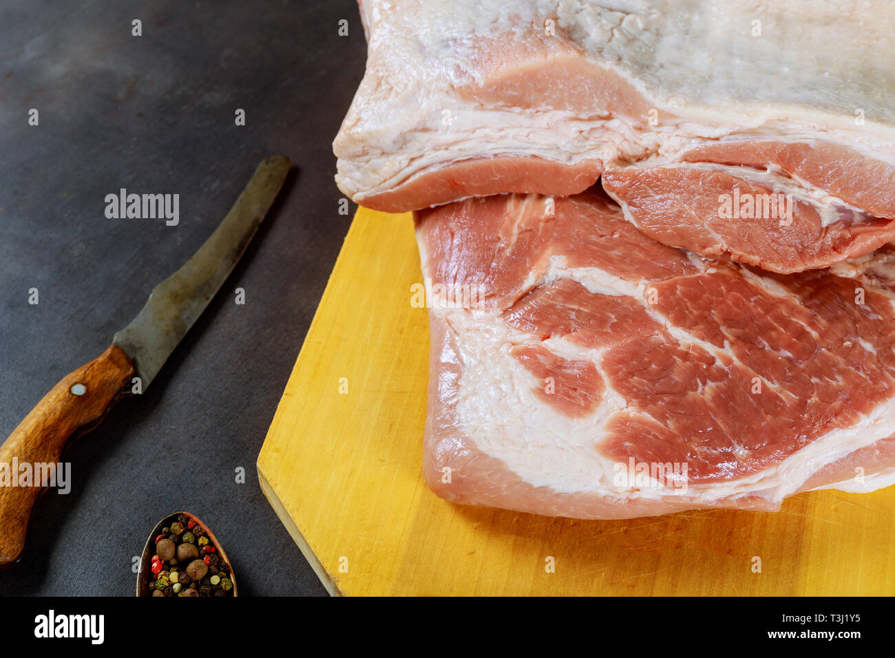 Cerdo crudo y la cuchilla en el fondo de madera. Foto de stock