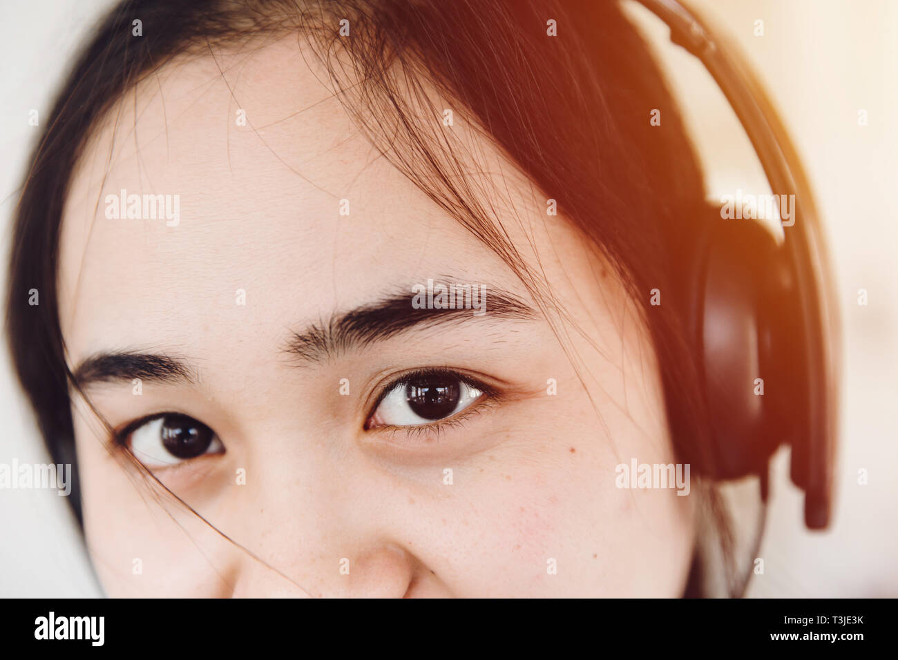 Asia mirando con ojos de color negro oscuro cejas cabello negro cute teen joven usando auriculares. Foto de stock