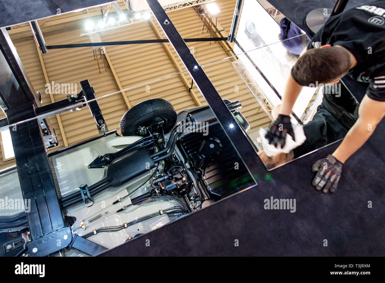 Essen, Alemania. 10 abr, 2019. En la Techno Classica, un empleado limpia un  espejo mostrando los bajos de la carrocería de un Mercedes-Benz 280 SL  pagoda para vintage y los coches clásicos.