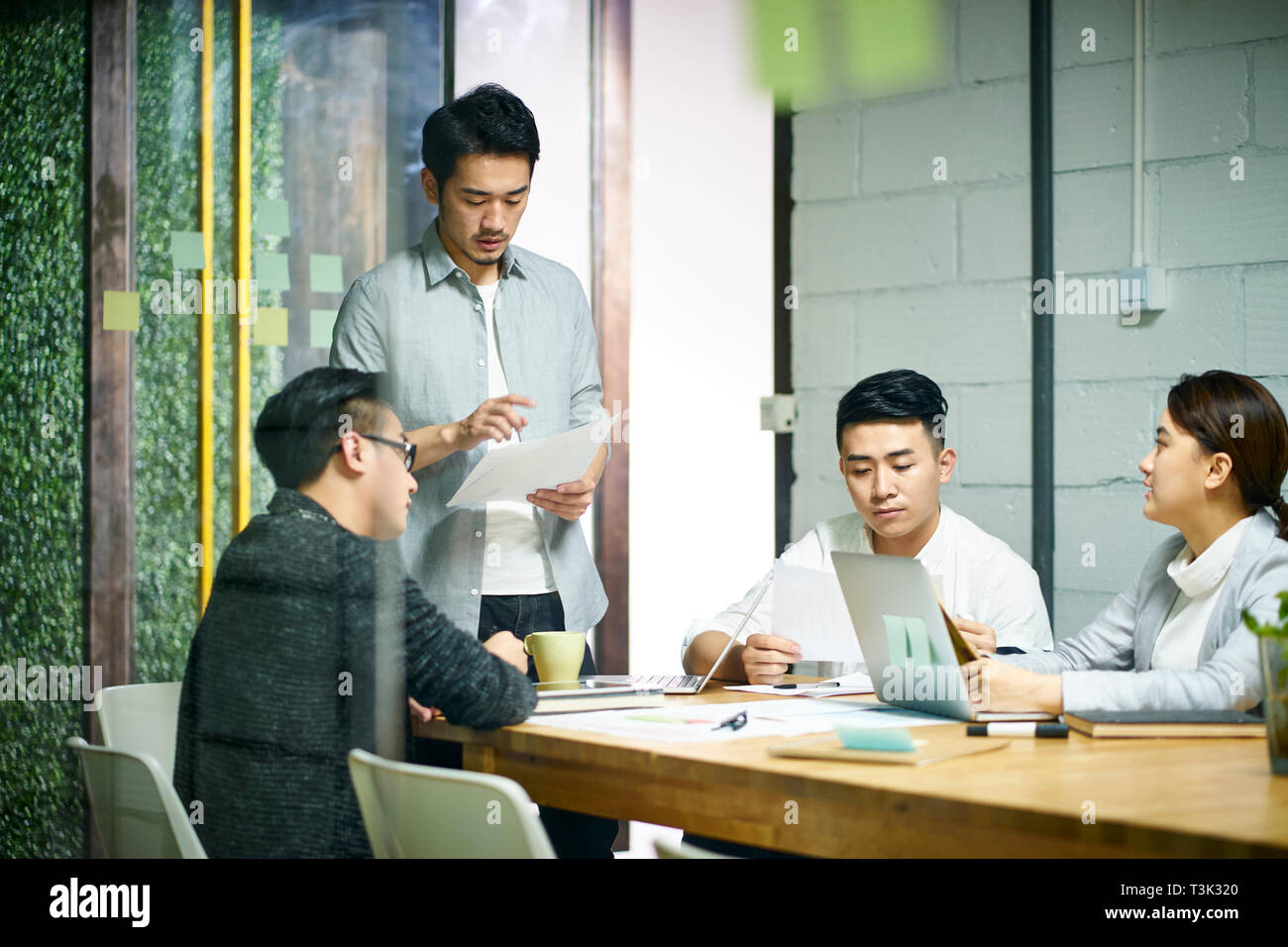 Los jóvenes empresarios asiáticos de pequeña empresa hablando sobre plan de negocios en la sala de reuniones de la oficina. Foto de stock