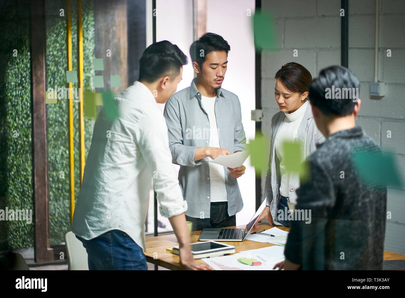 Los jóvenes empresarios asiáticos de pequeña empresa hablando sobre plan de negocios en la sala de reuniones de la oficina. Foto de stock