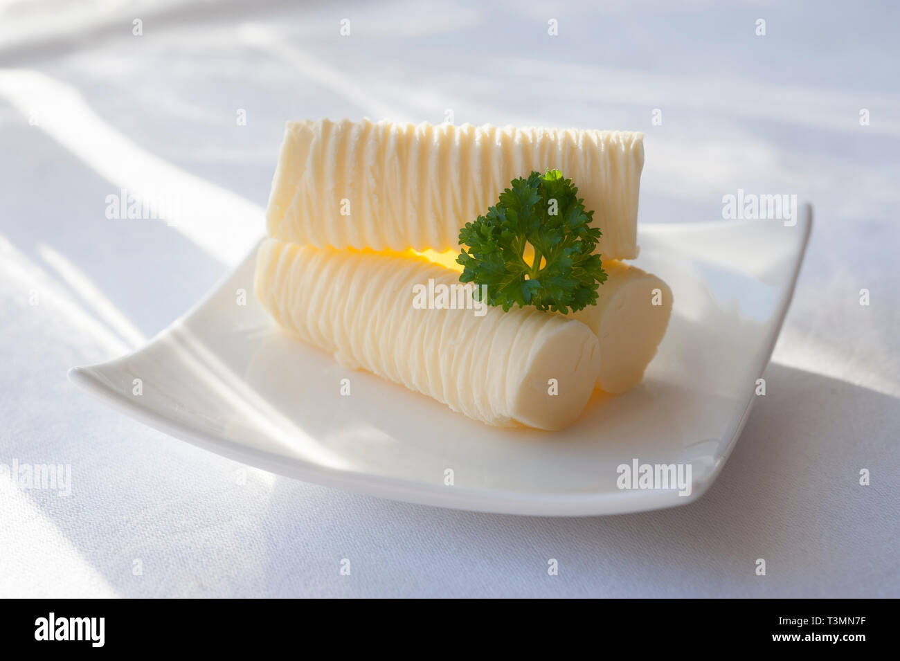 Panecillos de mantequilla con una guarnición de perejil en una soleada mesa Foto de stock