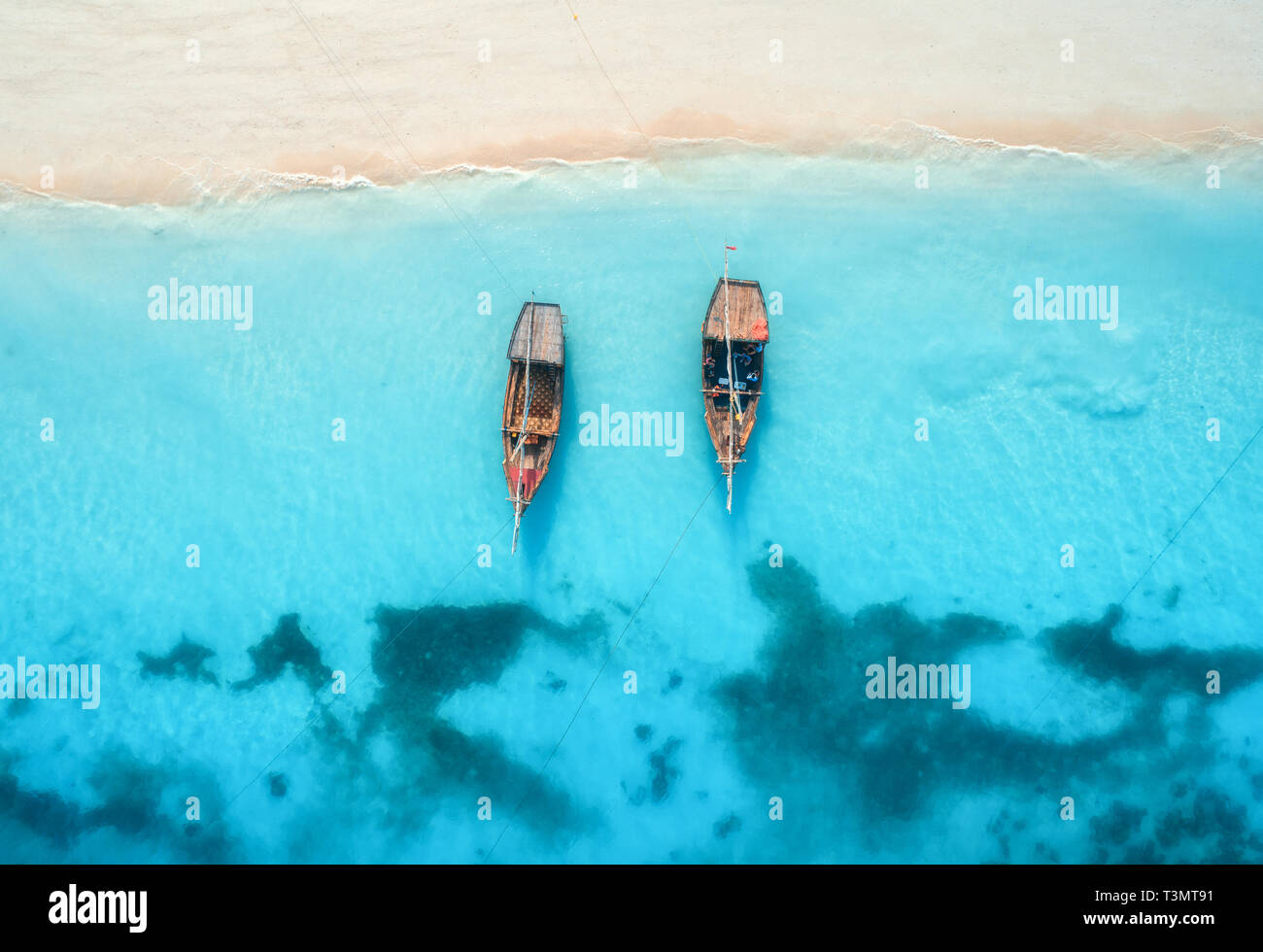 Vista aérea de las barcas en el agua azul claro al atardecer en verano. Vista superior del zumbido de barco, playa de arena. Océano Índico. Viajes en Zanzíbar, Foto de stock