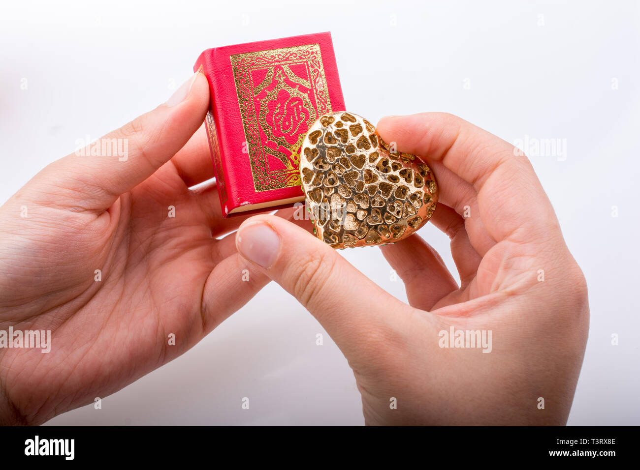 Mano que tiene forma de corazón y libro sagrado islámico Corán Foto de stock