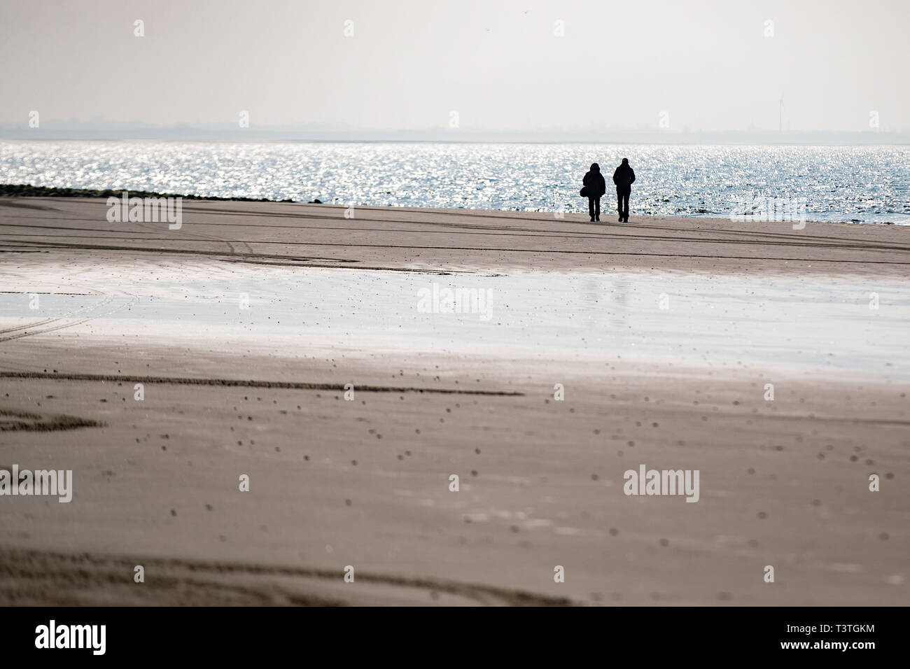 Zwei Personen laufen am Strand von Norderney Foto de stock