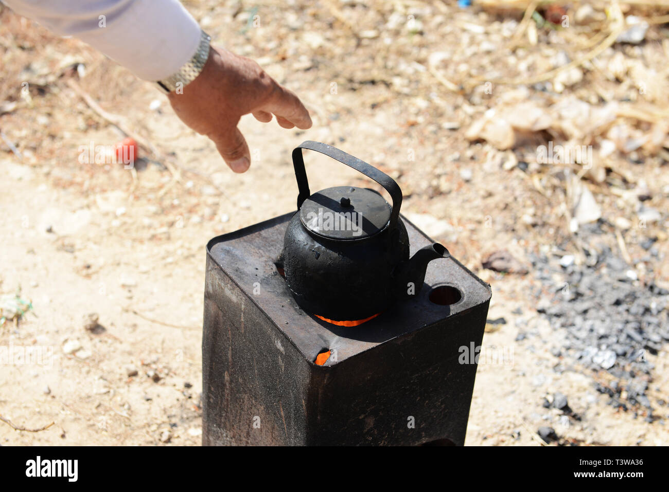 Un hombre beduino calentar agua caliente para una taza de café tradicional beduina en el desierto de Jordania. Foto de stock