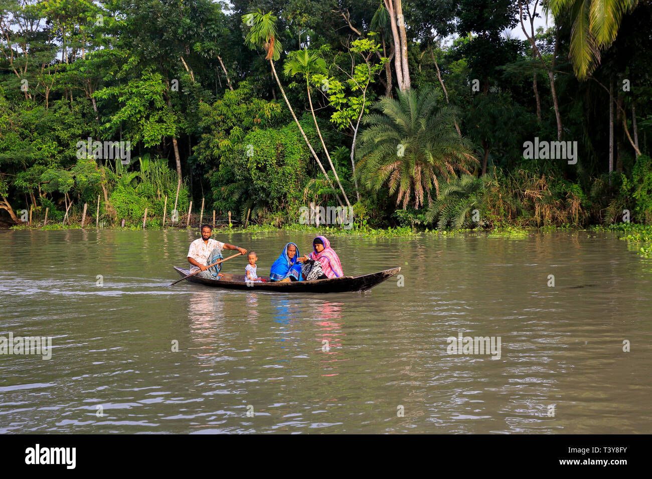 Una familia rural viaja en un pequeño bote a Najirpur Pirojpur en Bangladesh. Foto de stock