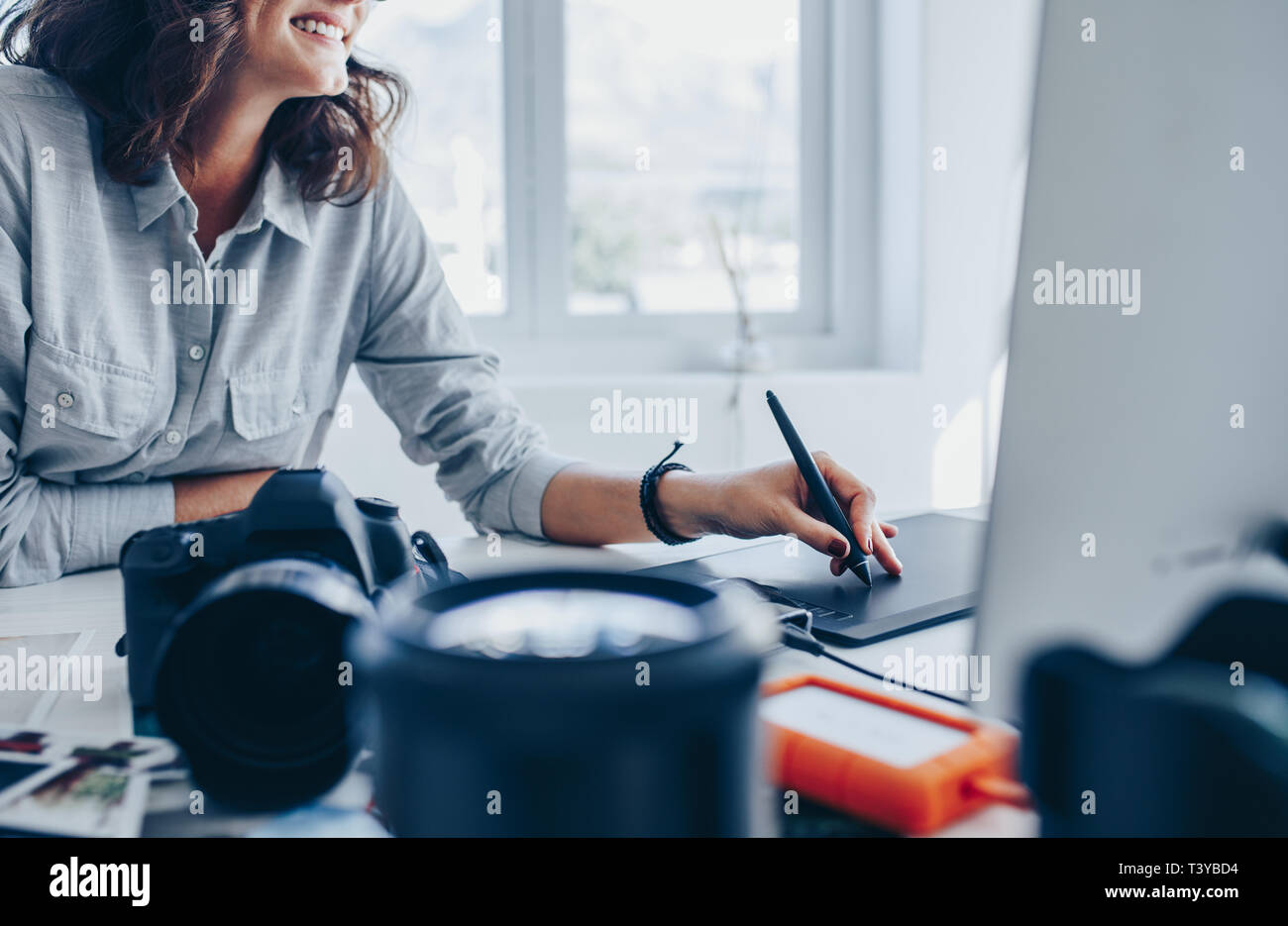 Fotógrafo de mujeres trabajando en equipo utilizando el Bloc de dibujo en su escritorio. Mujer joven con tableta gráfica y dibujo a lápiz de retoque de imágenes. Foto de stock