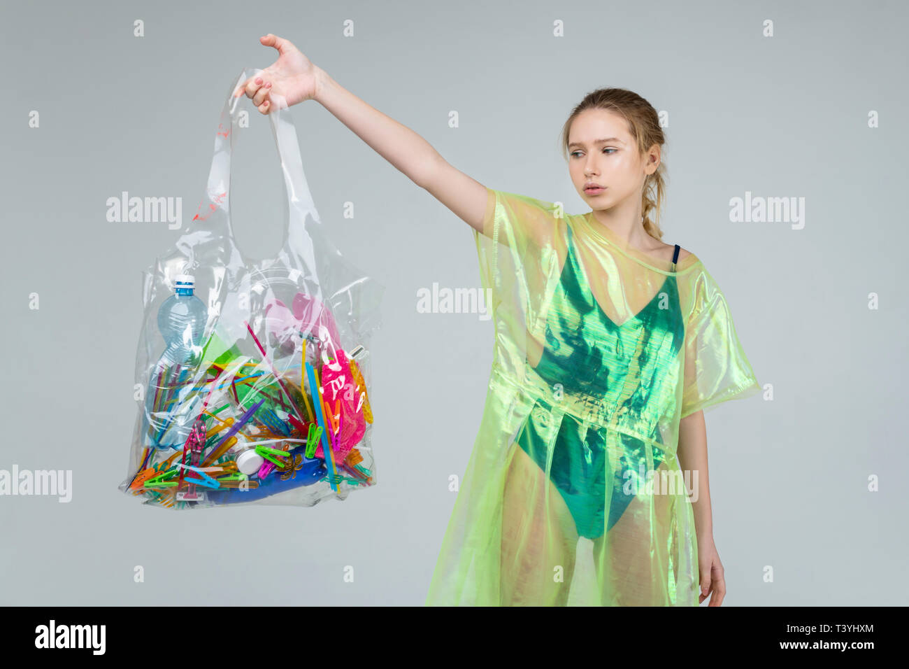 Cosas de plástico. Rubio modelo en ropa de plástico sujetando bolsa transparente de plástico en mano Fotografía stock - Alamy