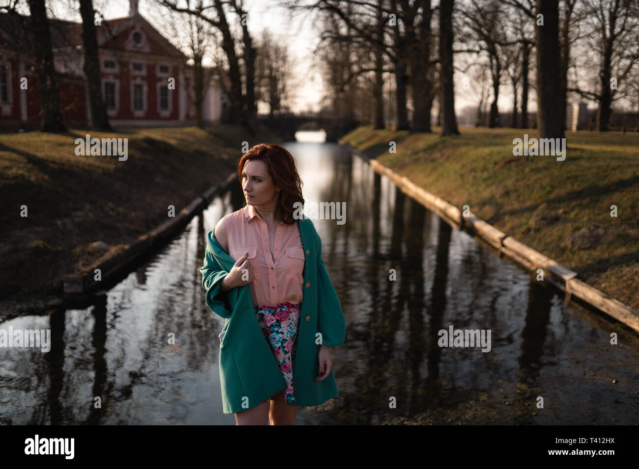 Hermosa joven relajante cerca de un canal río en un parque cerca del Palacio Rundale, Letonia, 2019 Foto de stock